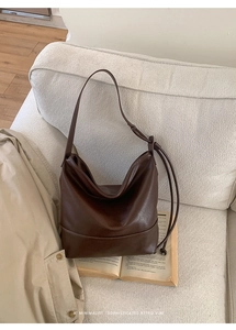 Detailed retro dark brown leather tote on a beige sofa with decorative ball pendant detail