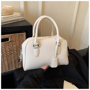 Close-up of white lychee pattern leather bowling bag with metallic ring and tag details