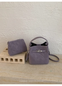 Detail of purple faux leather bucket bag set with rotating metal clasp and visible stitching