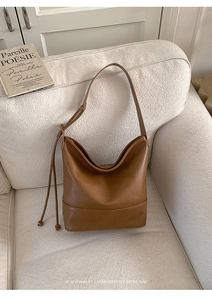 Detail of dark brown hobo shoulder bag featuring stylish side drawstring knot on sofa