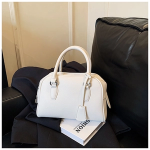 Detail of white lychee pattern bowling bag showing silver hardware and handle on a sofa