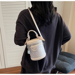 Detail of white cylinder bucket bag with geometric prints and silk scarf handle detail