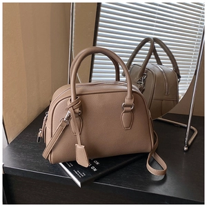Close-up of brown pebble grain leather Boston bag with silver hardware and adjustable strap