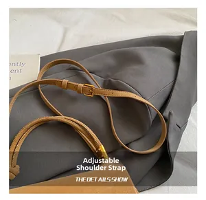 Détail de la bandoulière réglable en cuir marron avec boucle dorée et surpiqûres