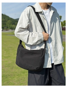 Detail view of the black nylon messenger bag with adjustable strap and textured finish