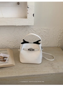 Detailed close-up of a white leather bucket bag with silver hardware on a stone base