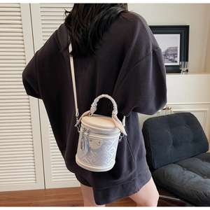 Detail of white cylinder bucket bag with geometric embroidery and scarf wrapped handle