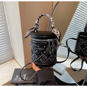 Detail of black bucket bag with geometric maze pattern and silk scarf handle decoration