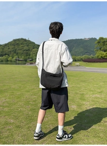 Detailed back view of a black lightweight nylon crossbody bag in an outdoor setting