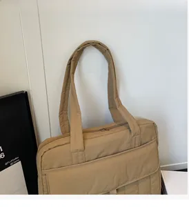 Detail der khakifarbenen gesteppten Nylontasche mit Frontklappe und breiten Tragegurten
