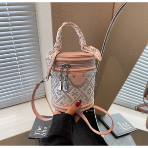 Close-up of pink bucket bag with geometric texture, heart scarf handle, and metal logo tag