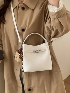 Minimalist beige bucket bag with metal turn-lock, crossbody strap and cute teddy charm