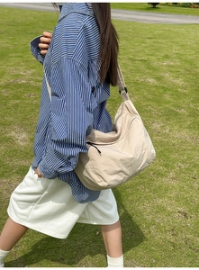 Detailed outdoor view of a cream nylon hobo bag with adjustable wide shoulder strap