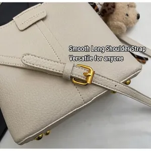 Detailed close-up of cream lychee leather bucket bag with gold hardware and shoulder strap