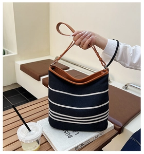 Detail of adjustable brown leather shoulder strap on a striped canvas tote bag