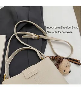 Detail of beige textured leather bucket bag with adjustable strap and cute puppy charm