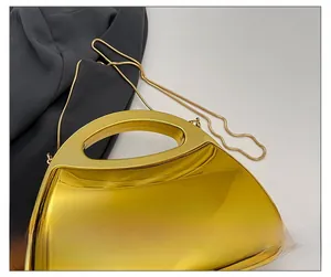 Macro shot of luxury gold acrylic clutch with polished mirror surface and snake chain strap