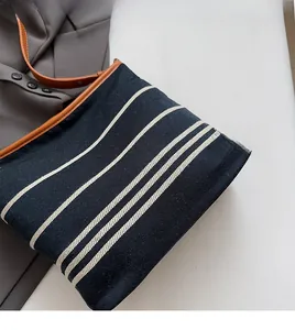 Close-up of navy canvas tote bag with white stripes and brown leather shoulder straps