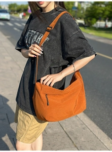 Detail of orange nylon crossbody bag with zipper pocket and adjustable strap on a model