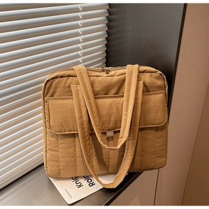 Makroansicht der khakifarbenen Stepptasche mit feiner Textur und vorderer Klappentasche