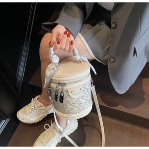 Detail of beige cylinder bucket bag with patterned panel and heart print silk scarf