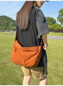 Outdoor shot of burnt orange nylon crossbody bag showing its large capacity and texture