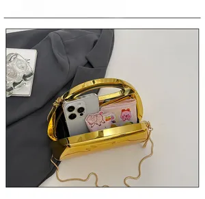 Macro view of gold mirror acrylic evening clutch with chain strap and internal storage space