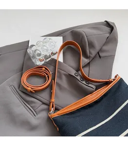 Detail view of navy blue striped canvas bucket bag with brown leather straps and metal hardware