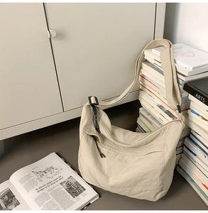 Top view of beige nylon hobo bag on books and magazines for daily casual lifestyle