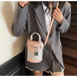 Detail of pink cylindrical bucket bag with geometric patterns and silk scarf handle decor