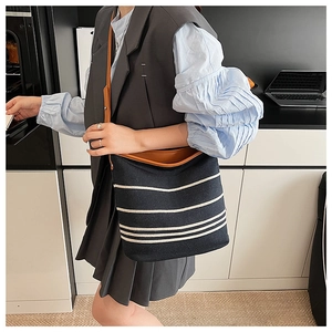 Detail of navy striped canvas bucket bag with brown leather straps on a casual outfit