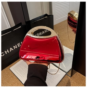 Detail of red acrylic box clutch bag with gold metal handle and reflective surface