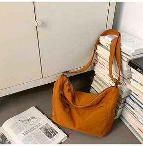 Detail of caramel nylon dumpling bag with adjustable strap in a cozy lifestyle setting
