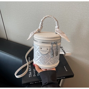 Close-up of beige bucket bag with retro floral jacquard pattern and scarf wrapped handle