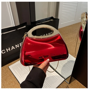 Macro shot of glossy red acrylic evening bag with a gold metal handle and chain strap