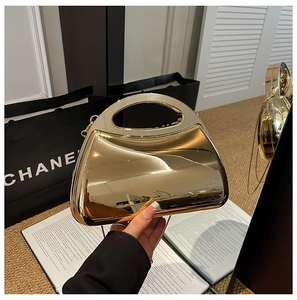 Macro shot of luxury gold mirror evening bag showing high-gloss metal finish and handle
