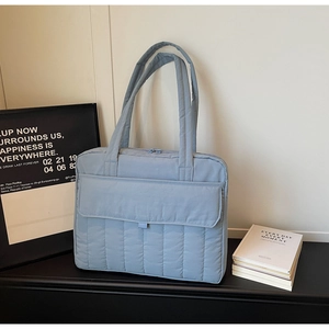 Nahaufnahme der blau gesteppten Tragetasche mit Vordertasche auf schwarzem Schreibtisch