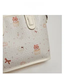 Primer plano del estampado de gato y la textura de cuero en el bolso color crema