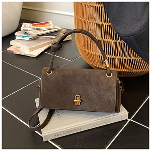 Detail of vintage dark brown suede handbag featuring a gold twist lock and metal handle rings