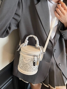 Chic cream bucket bag with jacquard fabric and scarf-wrapped handle on a fashion model