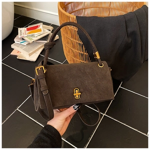 Détail d'un sac à main en daim marron foncé avec fermoir doré et texture raffinée