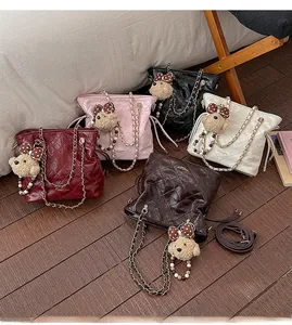 Flat lay of quilted bucket bags in five colors with cute bear charms on wood floor
