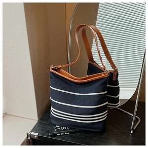 Detail view of large canvas tote with blue stripes and adjustable brown leather strap