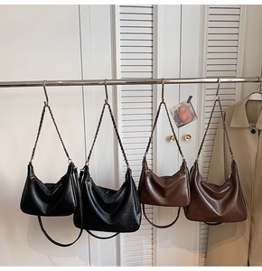 Detail view of retro faux leather tote bags in black and caramel with chain straps
