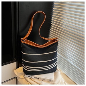 Close-up of black canvas tote bag with white stripes and brown leather strap detail