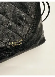Détail de la texture cuir matelassé noir et logo doré sur le sac seau élégant