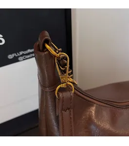 Close-up of pebble grain leather texture and vintage gold hardware on brown tote bag