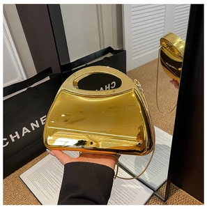 Macro shot of glossy gold acrylic clutch bag with round top handle and fine metal chain