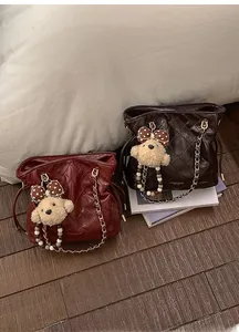 Close-up of quilted leather bucket bags with gold chain straps and plush bear charms