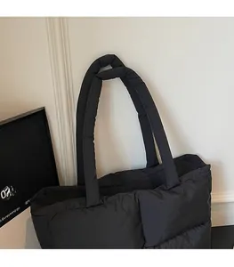 Detail of soft padded shoulder strap on black quilted puffer tote bag for winter